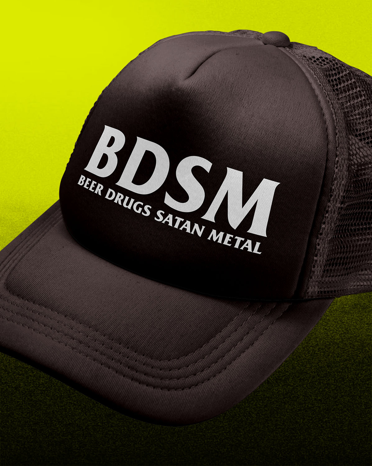 A black trucker-style cap with white text reading 'BDSM' and 'BEER DRUGS SATAN METAL' on the front panel, shown against a bright yellow-to-dark-green gradient background.