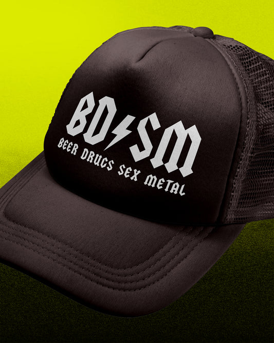 A black trucker hat with a white 'BO=SM' logo and the text 'BEER DRUGS SEX METAL' printed on the front panel, set against a bright yellow-green gradient background.