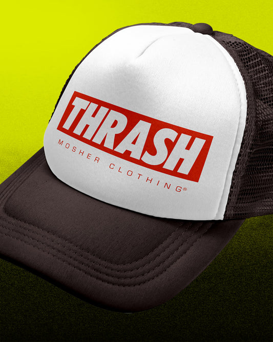A close-up of a trucker hat with a white front panel, black mesh back, and a bold red and white 'THRASH' logo on the front, set against a bright yellow-to-dark-green gradient background.